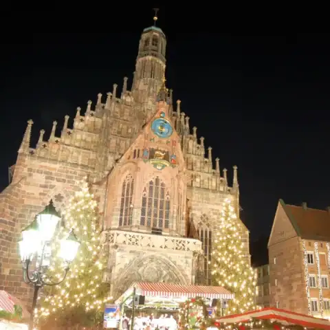 The Frauenkirche lit up at night above the Nuremberg Christmas market and its glowing Christmas trees