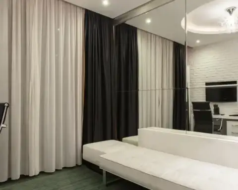 A modern city hotel room with striped curtains and a sofa, illustrating a standard to deluxe room upgrade.